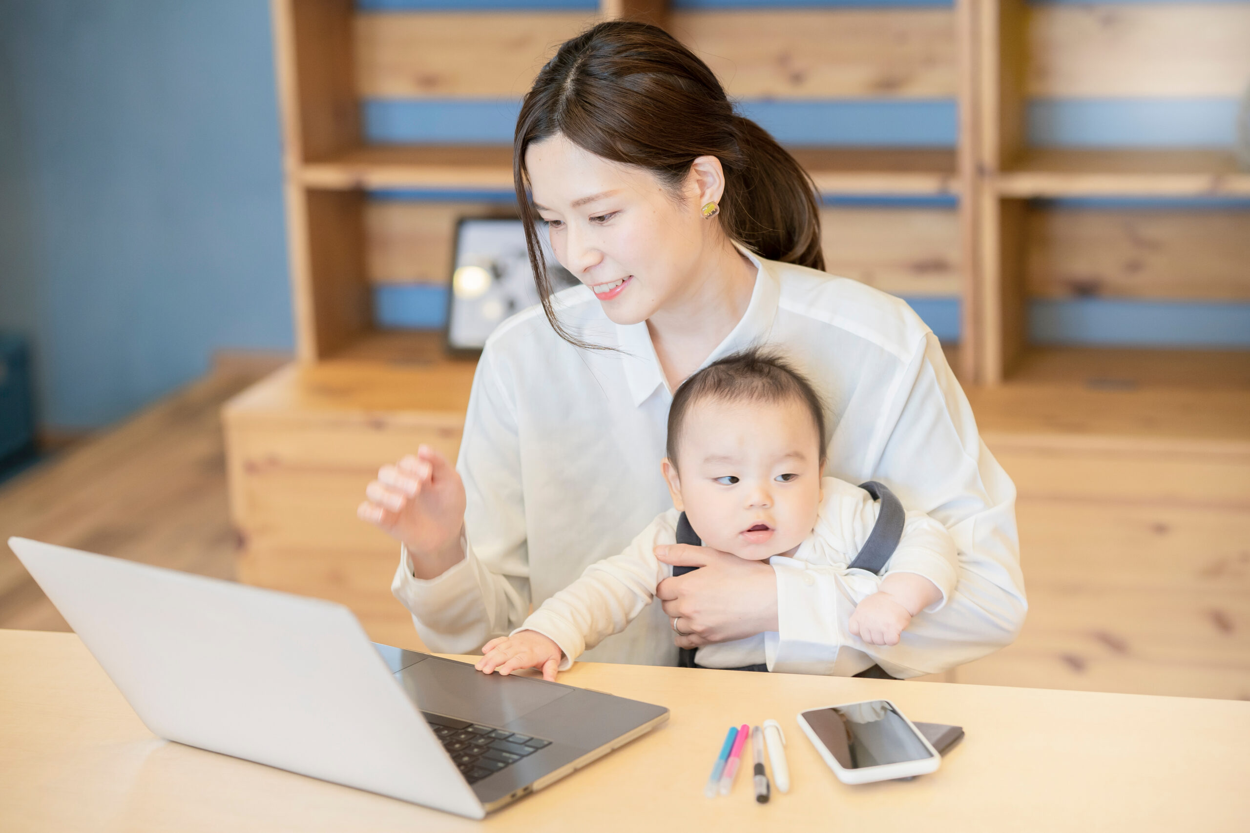 A,Woman,Holding,A,Baby,And,Operating,A,Laptop